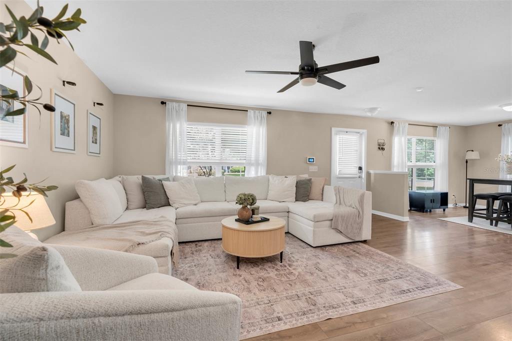 A living room features a large sectional sofa, a round coffee table, and a ceiling fan — 9548 CHARLESBERG DRIVE, TAMPA, FL