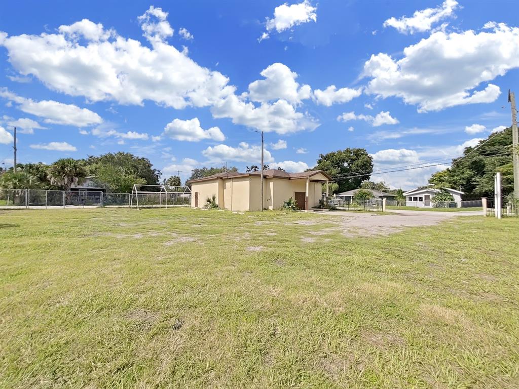 A large, grassy lot features a single-story tan building under a bright, cloudy sky — 4501 N 42ND STREET, TAMPA, FL