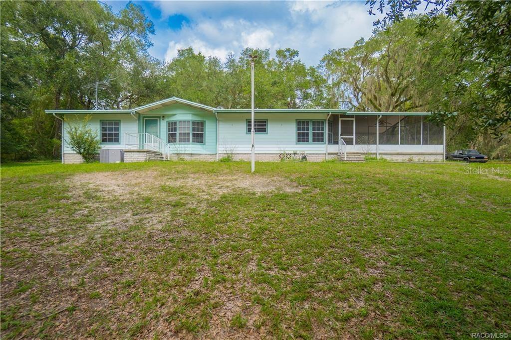 A light green single-story house with a screened-in porch sits on a grassy lot — 9300 CR 647A, BUSHNELL, FL