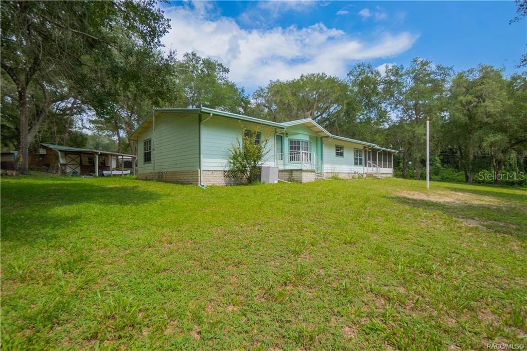 A light green single-story house with a metal roof sits on a grassy lot — 9300 CR 647A, BUSHNELL, FL