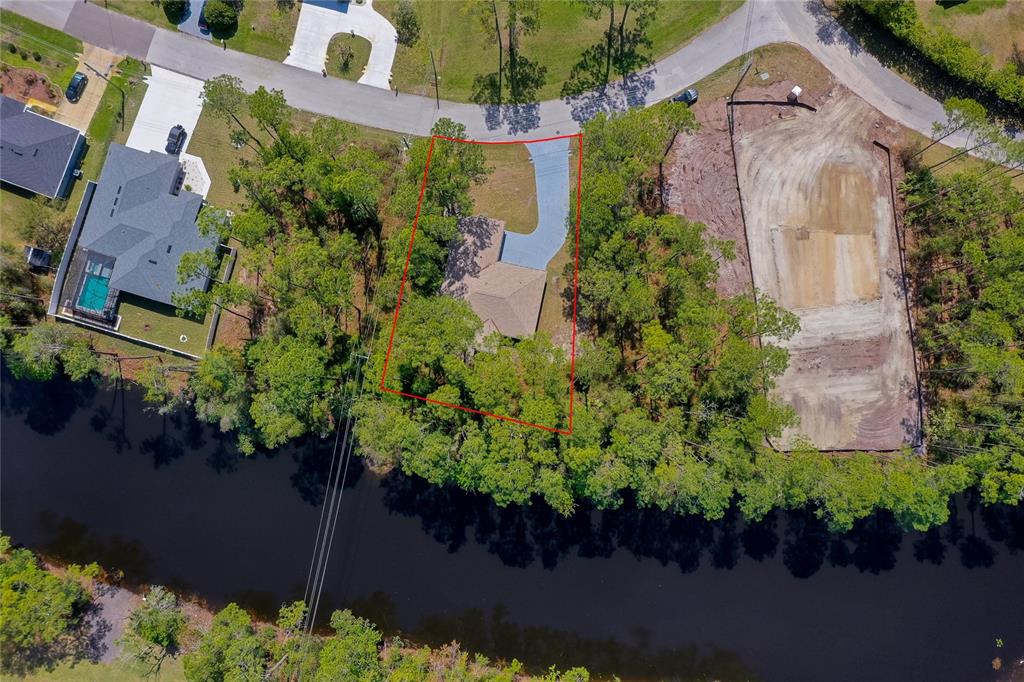 An aerial view shows a house with a driveway situated on a wooded waterfront lot — 7 PENINSULA LANE, PALM COAST, FL