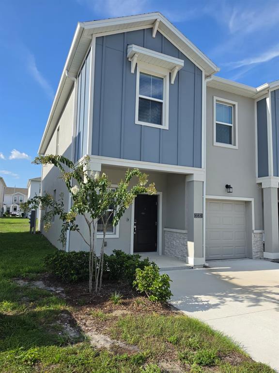 A two-story townhouse exterior features blue vertical siding, a gray garage, and a front entrance — 3330 LAURENT LOOP UNIT 3330, DAVENPORT, FL