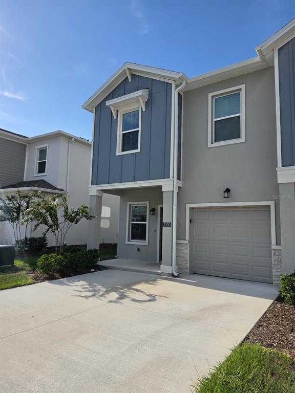 A two-story townhouse with a blue vertical-siding accent, gray stucco, and a single-car garage — 3330 LAURENT LOOP UNIT 3330, DAVENPORT, FL