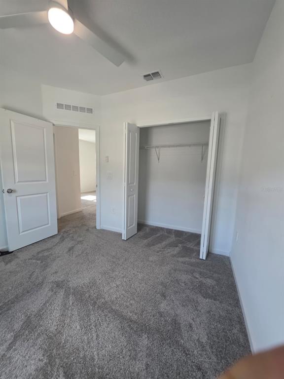 A bedroom with gray carpet, a ceiling fan, a white door, and an open closet — 3330 LAURENT LOOP UNIT 3330, DAVENPORT, FL
