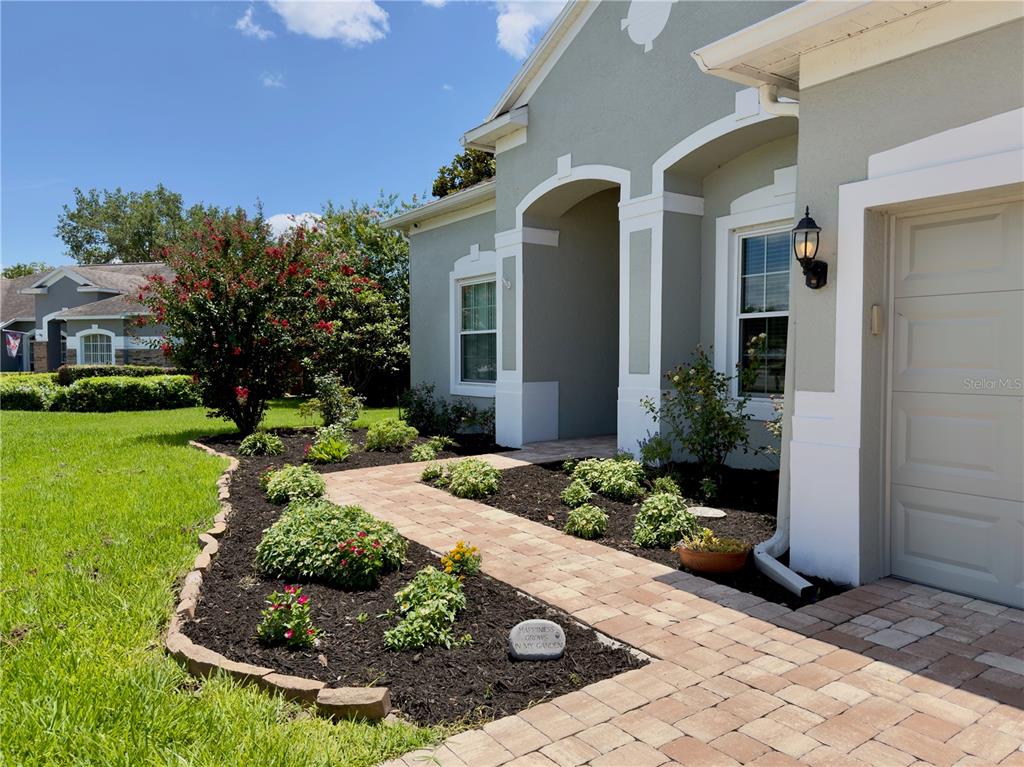 A paved walkway leads to the front entrance of a house with light green siding — 2006 WINTERMERE POINTE DRIVE, WINTER GARDEN, FL