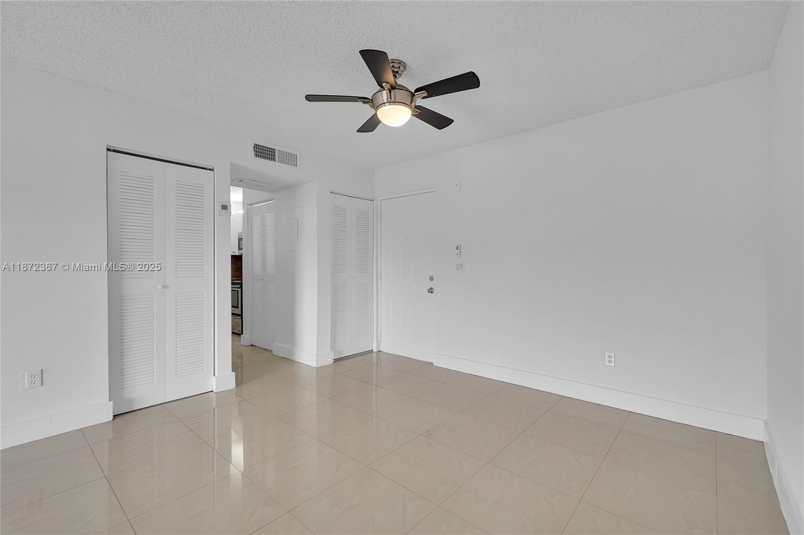 An empty room features white walls, light-colored tile flooring, and a ceiling fan — 8260 SW 210th St # 201, Cutler Bay FL 33189, CUTLER BAY, FL