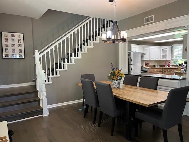 A dining area with a wooden table, dark chairs, and a staircase with white railings — 14202 NELL DRIVE, ORLANDO, FL