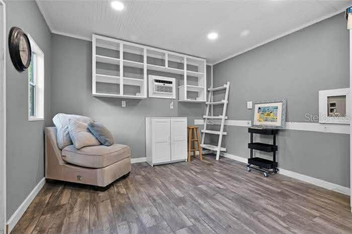 A room with gray walls, wood-look flooring, built-in shelving, and a beige armchair — 14202 NELL DRIVE, ORLANDO, FL