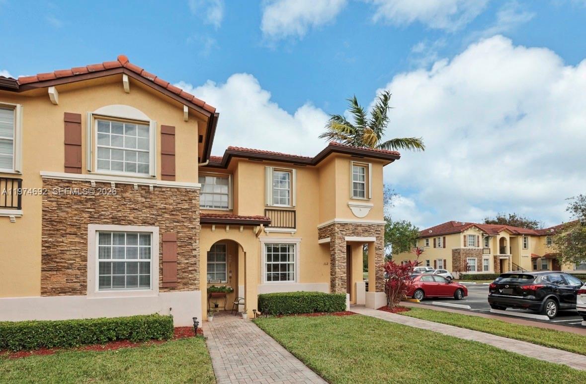 A two-story stucco townhouse features stone veneer accents, a tiled roof, and a paved walkway — 1650 NE 33rd Rd # 10, Homestead FL 33033, HOMESTEAD, FL