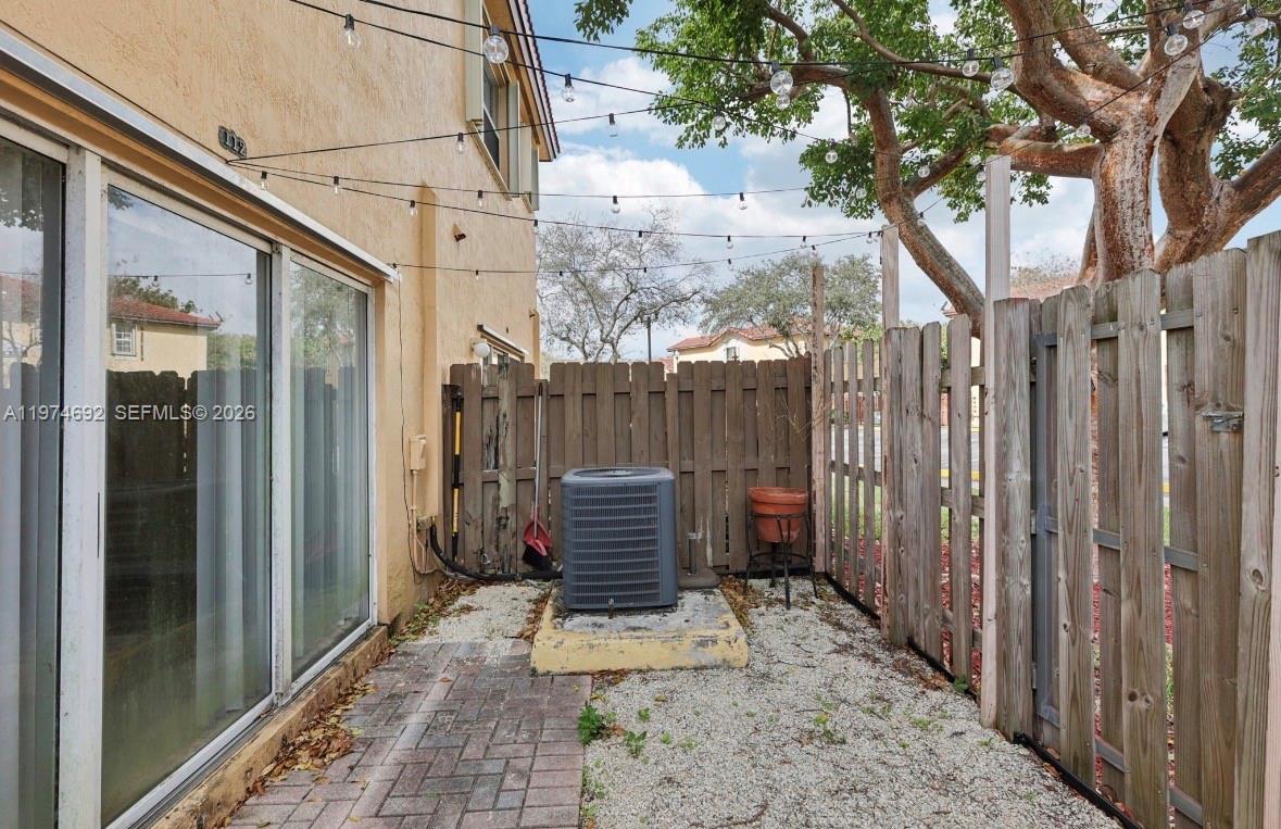 A small patio area features an air conditioning unit, gravel ground, and a wooden fence — 1650 NE 33rd Rd # 10, Homestead FL 33033, HOMESTEAD, FL
