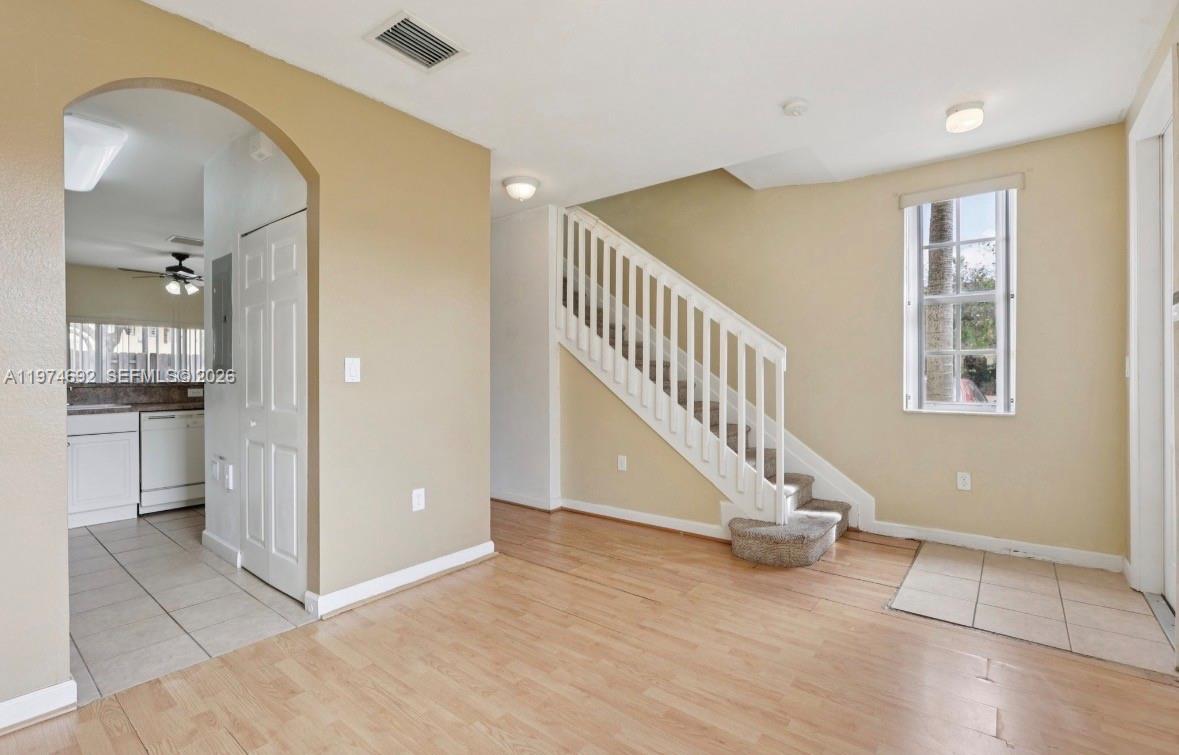 An interior view shows a living area with light wood flooring, stairs, and a kitchen — 1650 NE 33rd Rd # 10, Homestead FL 33033, HOMESTEAD, FL