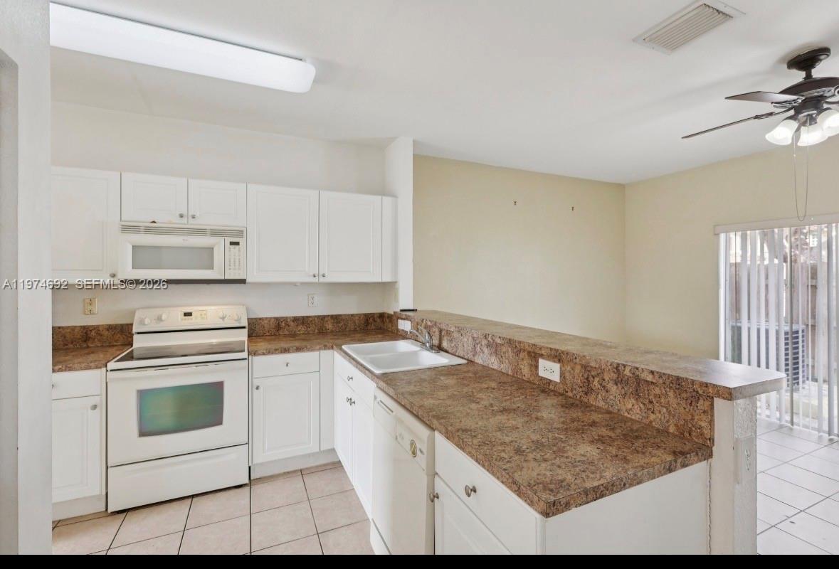 A kitchen with white cabinets, brown laminate countertops, white appliances, and tile flooring — 1650 NE 33rd Rd # 10, Homestead FL 33033, HOMESTEAD, FL