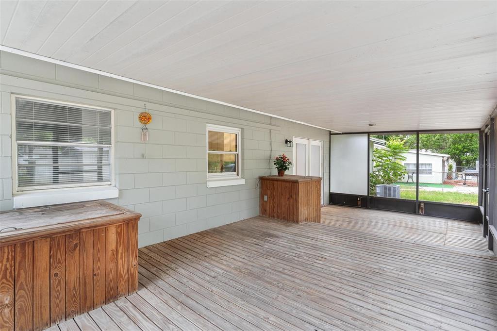 A covered wooden deck features a light green concrete block wall and screened-in porch area — 35904 DAWN DRIVE, LEESBURG, FL