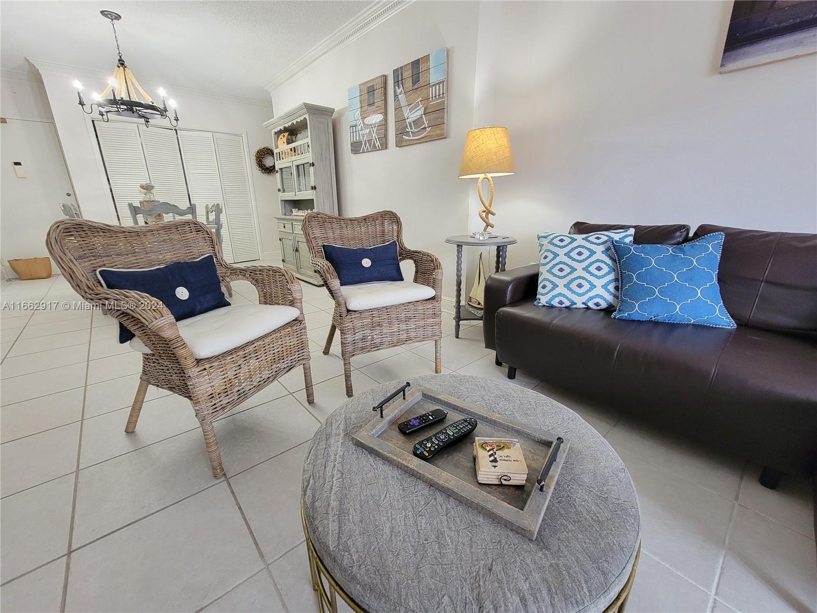 A living room features wicker chairs, a dark leather sofa, and a round ottoman — 1980 S Ocean Dr # 2C, Hallandale Beach FL 33009, HALLANDALE BEACH, FL