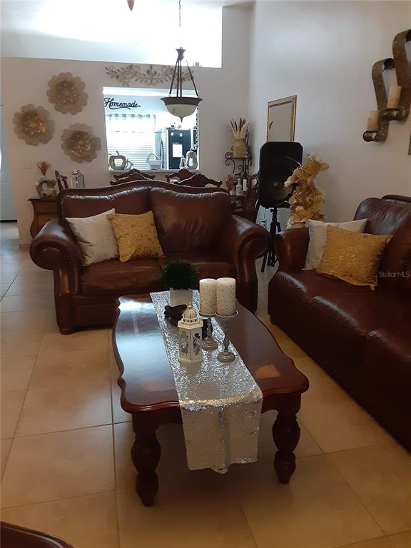 A living room features two brown leather sofas, a coffee table, and tile flooring — 14364 ISLAND COVE DRIVE, ORLANDO, FL