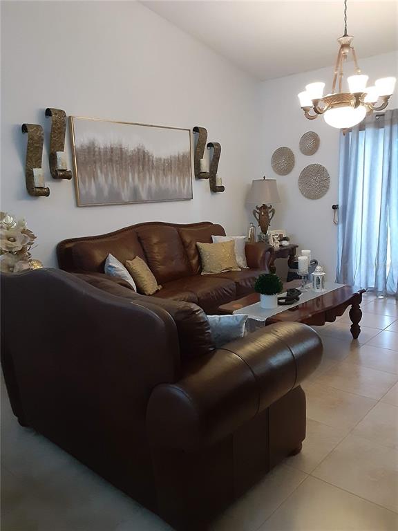 A living room features a brown leather sofa, a coffee table, and wall-mounted decor — 14364 ISLAND COVE DRIVE, ORLANDO, FL