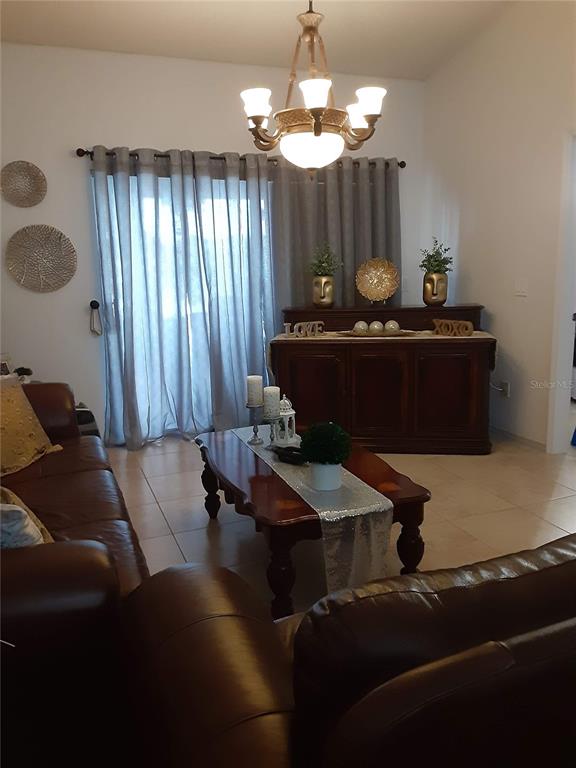 A living room features a brown leather sofa, a wooden coffee table, and a sideboard — 14364 ISLAND COVE DRIVE, ORLANDO, FL