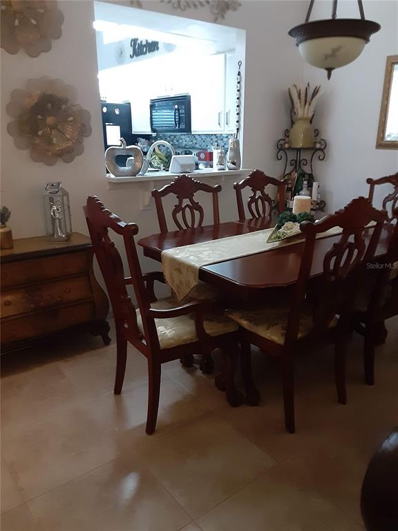 A dining room features a wooden table with chairs, a pass-through window, and tiled flooring — 14364 ISLAND COVE DRIVE, ORLANDO, FL