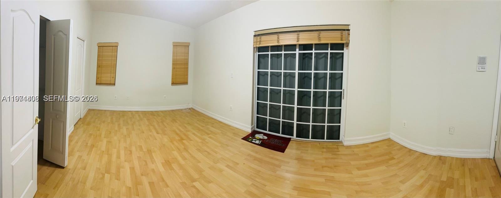 An empty room features light wood flooring, white walls, two windows, and a sliding glass door — 87** NW 150th Ter # 0, Miami Lakes FL 33018, MIAMI LAKES, FL
