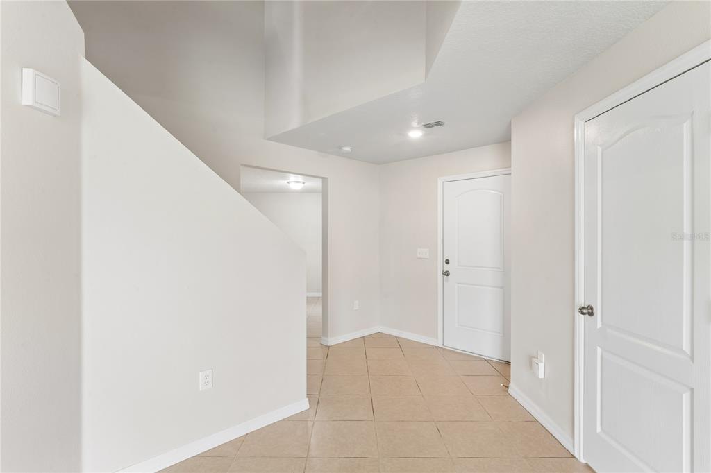 A bright entryway features beige tile flooring, white walls, and two closed interior doors — 2427 CASPIAN DRIVE, LAKELAND, FL