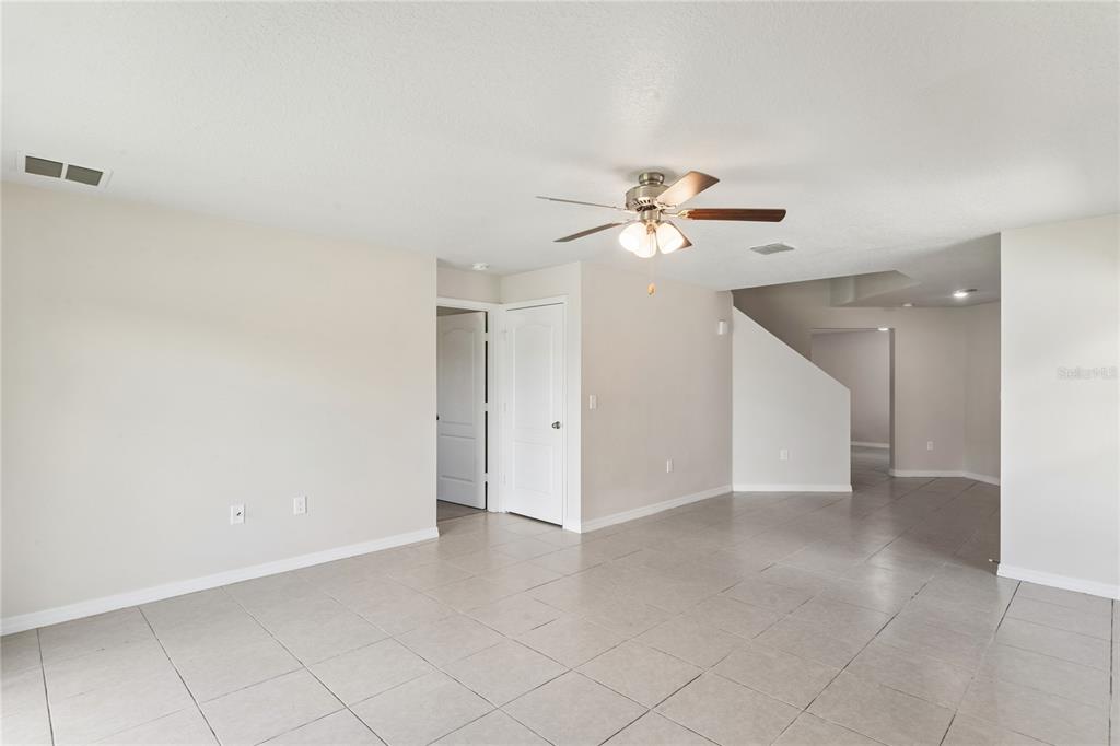 A spacious living room features light-colored tile flooring, white walls, and a ceiling fan — 2427 CASPIAN DRIVE, LAKELAND, FL
