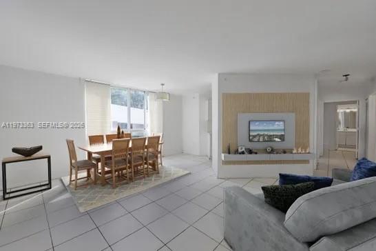 An open-concept living and dining area features white tile floors and a wood-paneled media wall — 1688 West Ave # 08, Miami Beach FL 33139, MIAMI BEACH, FL