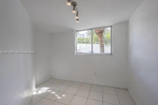 An empty room with white walls, white tile flooring, and a window overlooking palm trees — 1688 West Ave # 08, Miami Beach FL 33139, MIAMI BEACH, FL
