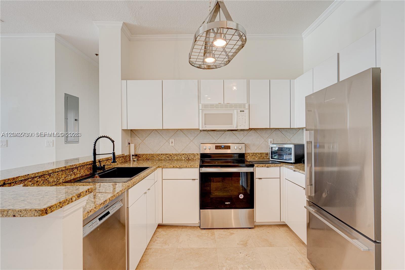 A kitchen features white cabinets, granite countertops, stainless steel appliances, and a hanging metal light — 2665 SW 37th Ave # 101, Miami FL 33133, MIAMI, FL