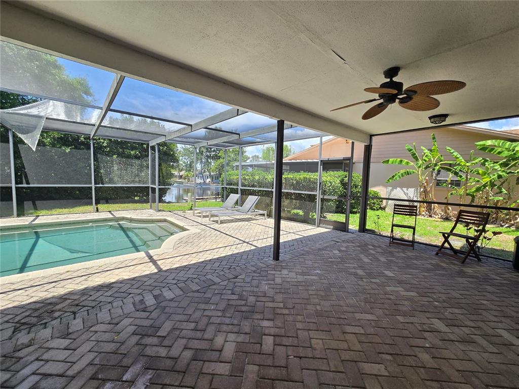 A covered patio features brick pavers, a ceiling fan, and a screened-in swimming pool area — 300 CYPRESS CREEK CIRCLE, OLDSMAR, FL