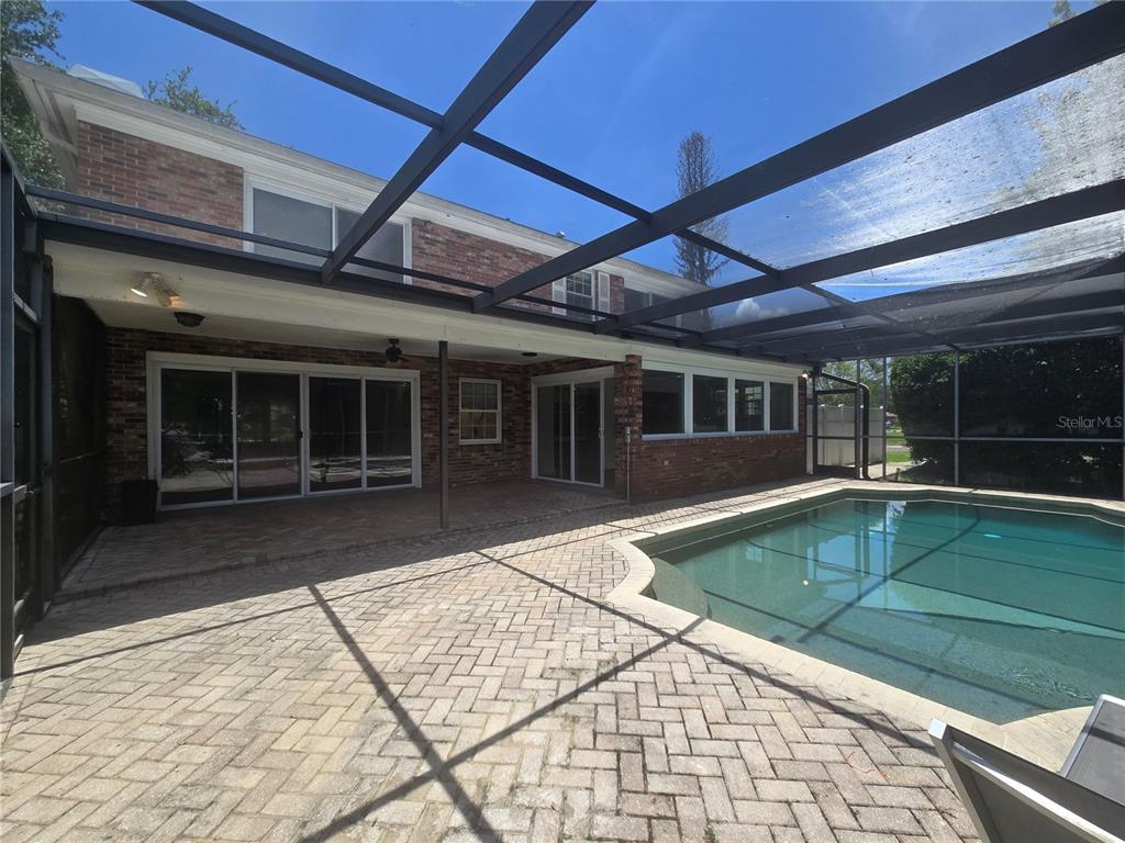 A brick house with a screened-in pool and paver patio under a metal cage enclosure — 300 CYPRESS CREEK CIRCLE, OLDSMAR, FL