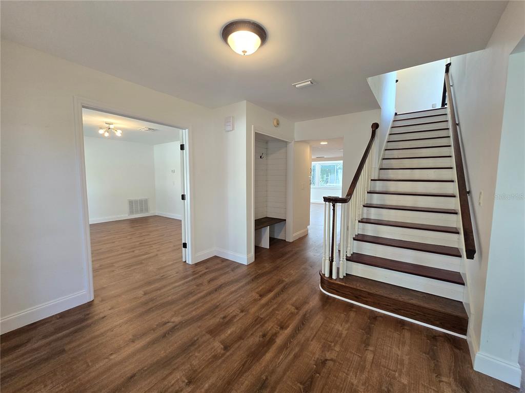 An entryway features wood-look flooring, a staircase with dark treads, and a built-in mudroom bench — 300 CYPRESS CREEK CIRCLE, OLDSMAR, FL