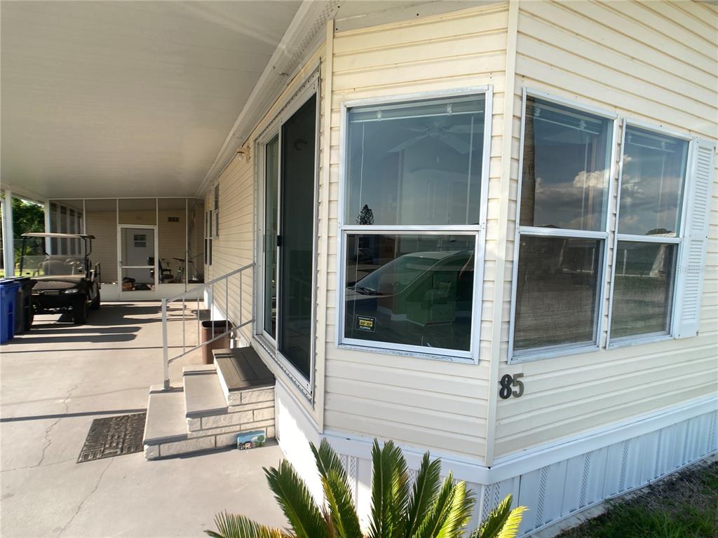 A view of a mobile home exterior featuring a carport, stairs, and large windows — 1710 7TH STREET SW UNIT 85, RUSKIN, FL