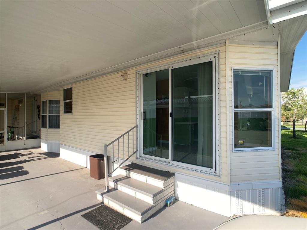 A sliding glass door leads to concrete steps under a covered carport of a mobile home — 1710 7TH STREET SW UNIT 85, RUSKIN, FL