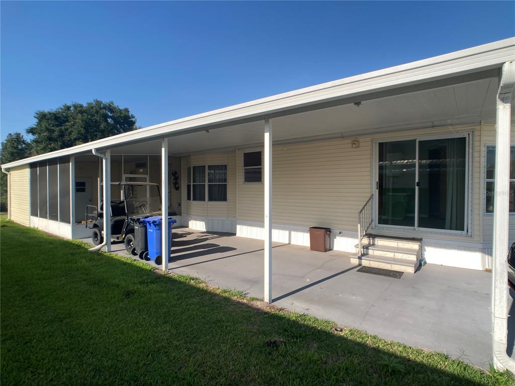 A covered concrete patio runs along the side of a light yellow manufactured home — 1710 7TH STREET SW UNIT 85, RUSKIN, FL