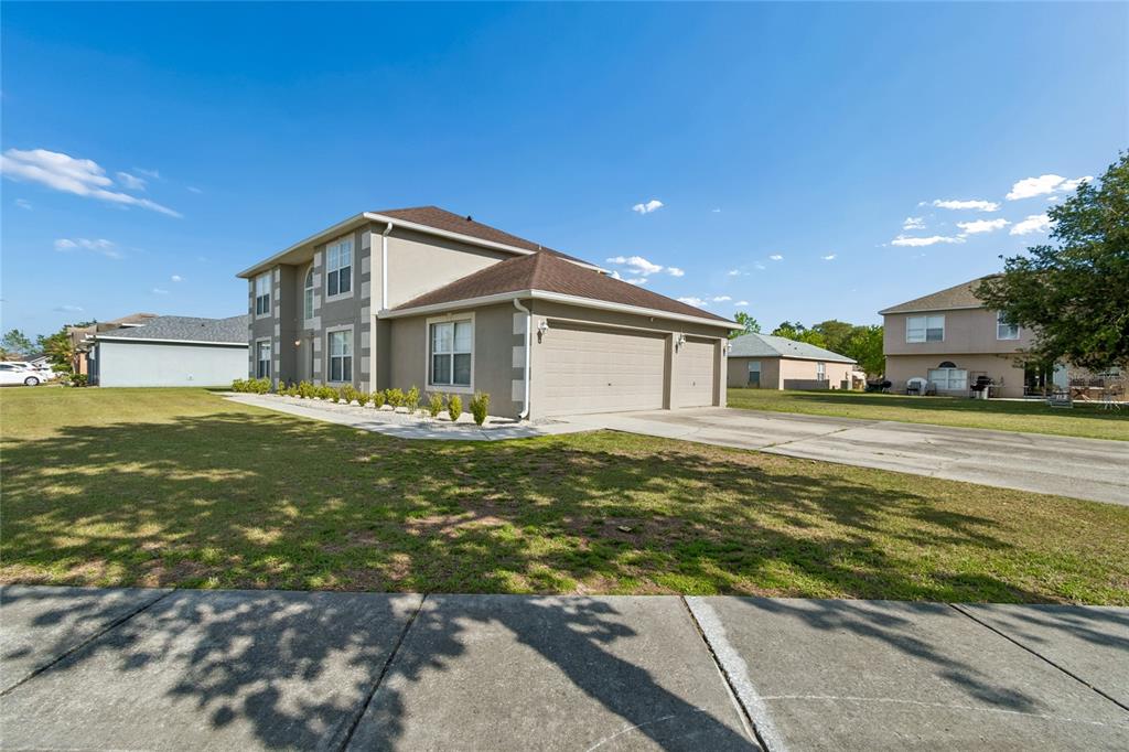 A two-story house with a tan stucco exterior, a brown roof, and a three-car garage — 2789 WOODLAND CREEK LOOP, KISSIMMEE, FL