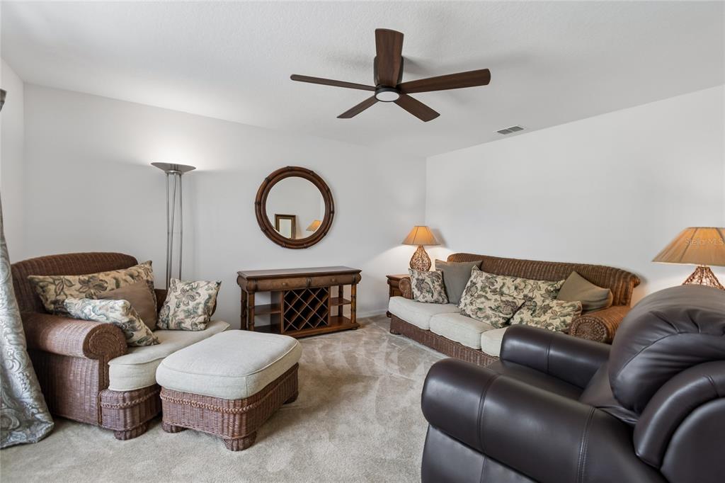 A living room features wicker furniture, a brown leather recliner, and a circular wall mirror — 2789 WOODLAND CREEK LOOP, KISSIMMEE, FL