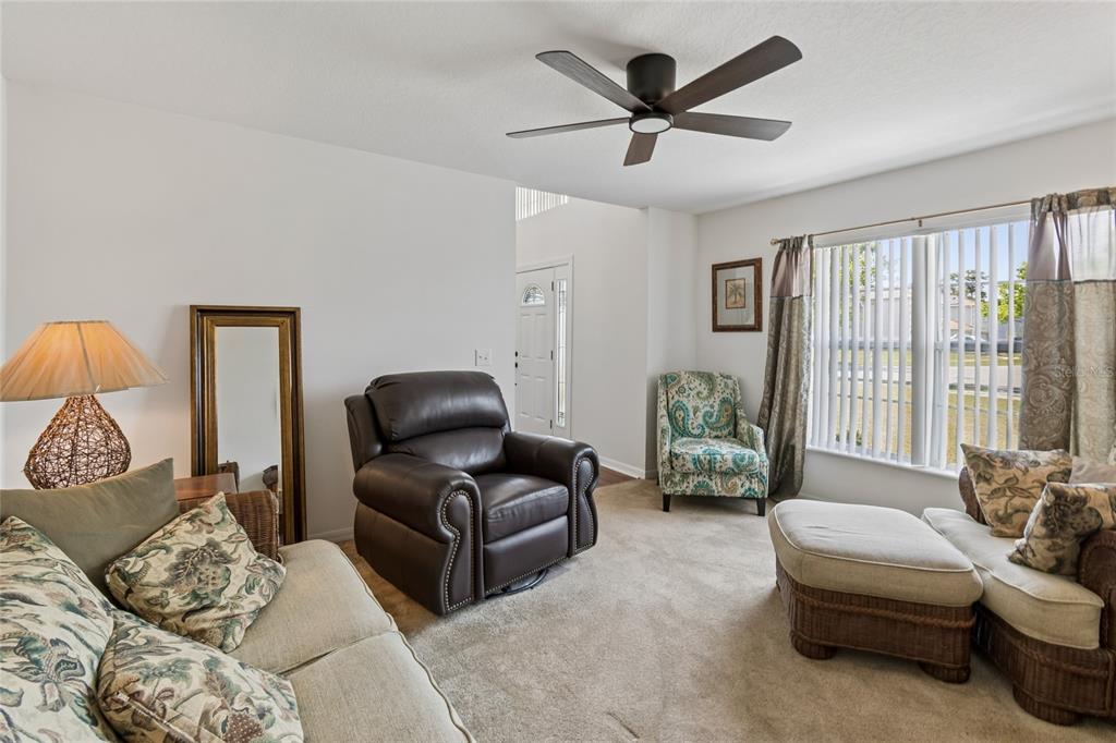 A living room features a ceiling fan, a leather recliner, and a patterned armchair — 2789 WOODLAND CREEK LOOP, KISSIMMEE, FL