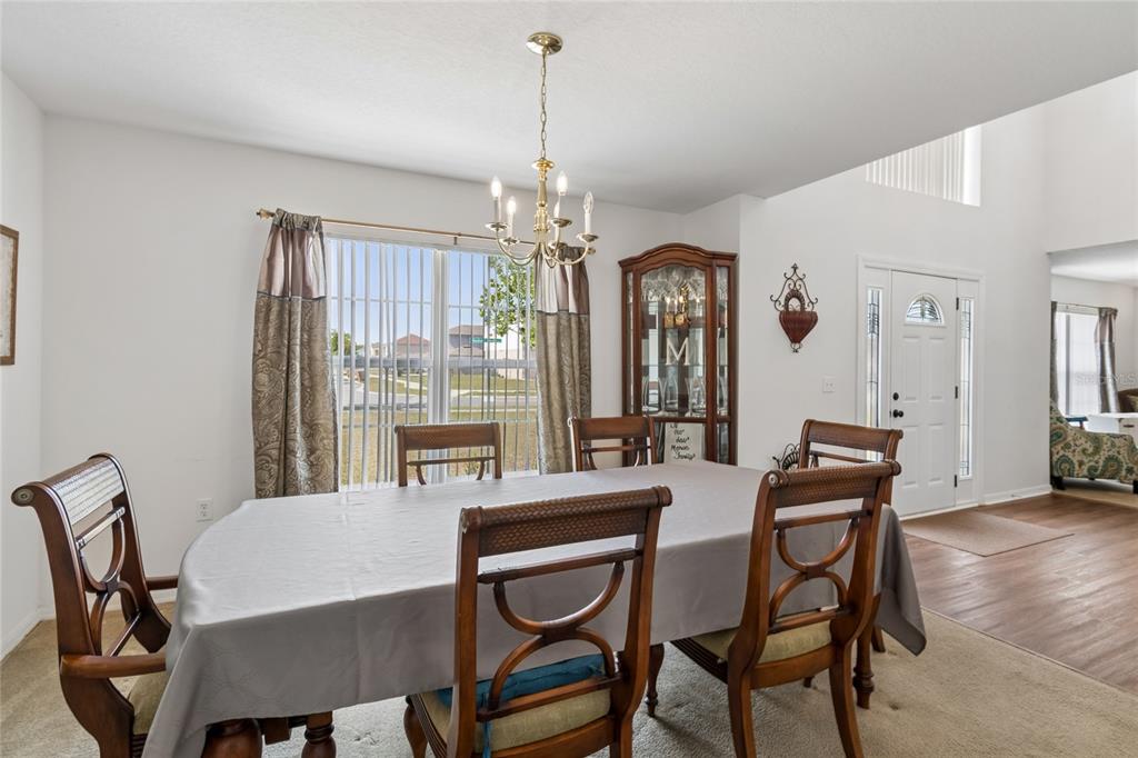 A dining room features a wooden table with six chairs, a chandelier, and a china cabinet — 2789 WOODLAND CREEK LOOP, KISSIMMEE, FL