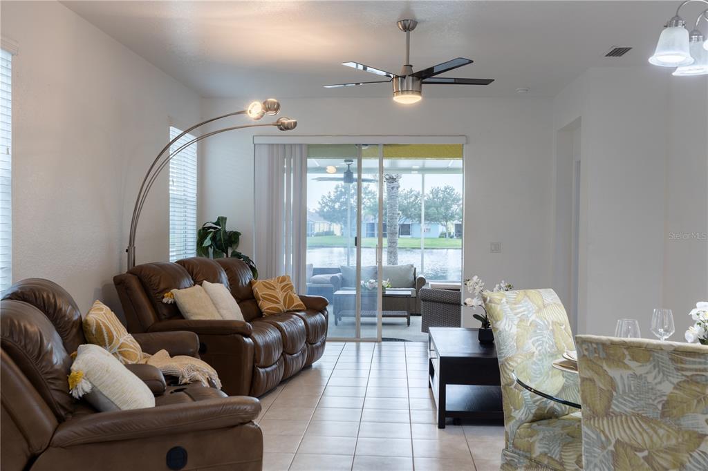 A living room with brown leather sofas, a floor lamp, and a view of a lake — 11447 CAPTIVA KAY DRIVE, RIVERVIEW, FL