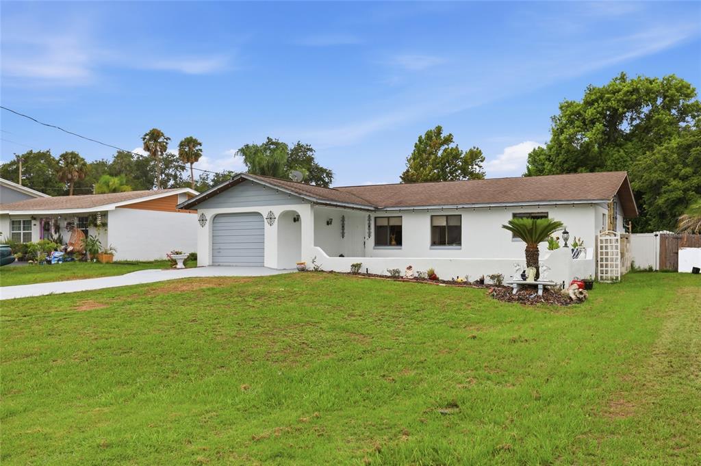 A single-story white house with a grey garage door and a large front lawn — 1025 PARK AVENUE, TAVARES, FL