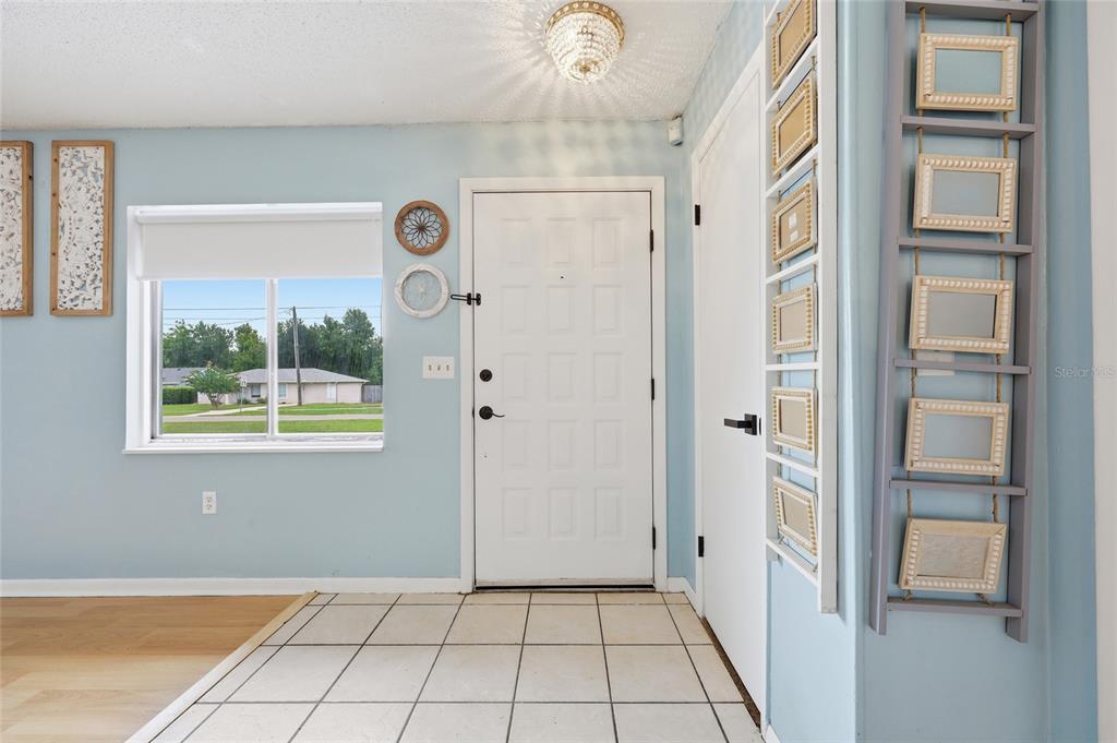 An entryway features light blue walls, a white front door, tiled flooring, and decorative wall hangings — 1025 PARK AVENUE, TAVARES, FL