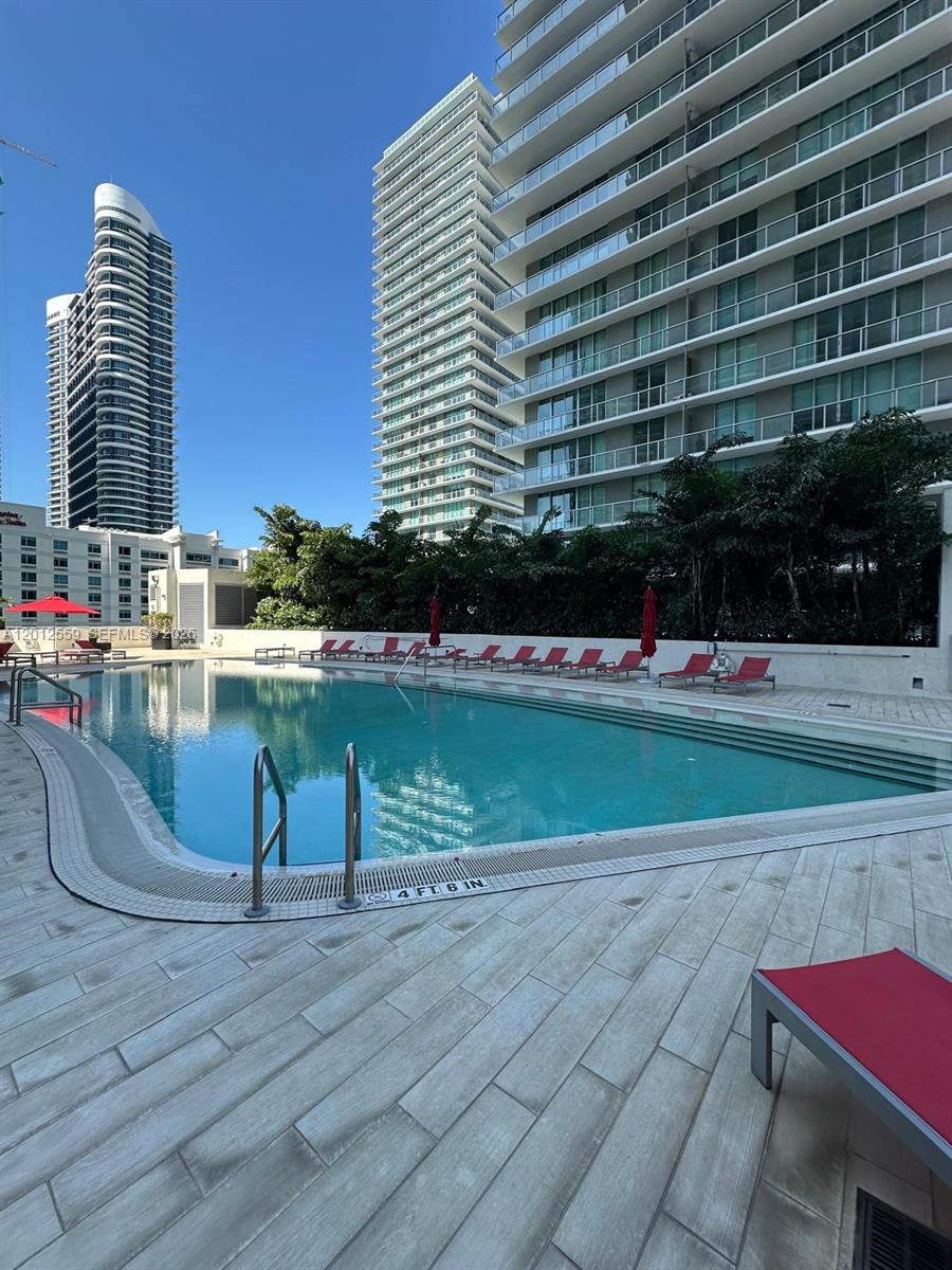 An outdoor swimming pool surrounded by lounge chairs and tall residential buildings — 1100 S Miami Ave # 2608, Miami FL 33130, MIAMI, FL