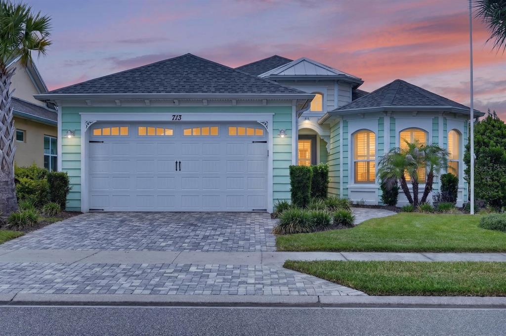 A light green house with a two-car garage and a paved driveway at sunset — 713 LANDSHARK BOULEVARD, DAYTONA BEACH, FL
