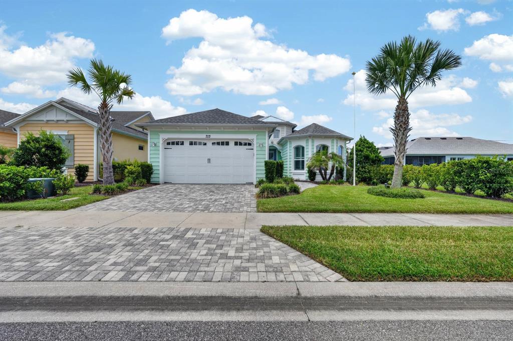 A light green house with a two-car garage and a paved driveway under a blue sky — 713 LANDSHARK BOULEVARD, DAYTONA BEACH, FL