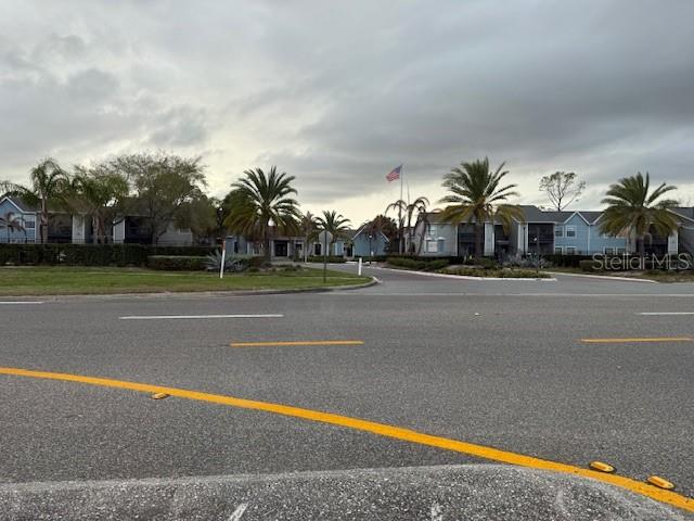 An exterior view of a multi-story apartment complex with palm trees under a cloudy sky — 3700 IDLEBROOK CIRCLE UNIT 112, CASSELBERRY, FL