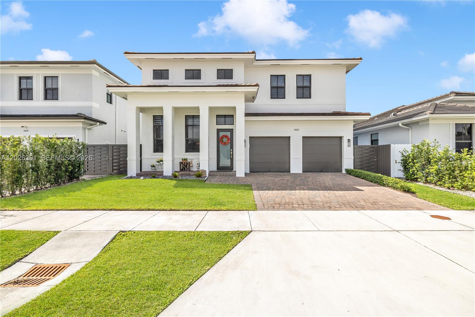 A two-story white house features a paved driveway, a two-car garage, and a front porch — 14606 SW 22nd Ter, Miami FL 33175, MIAMI, FL
