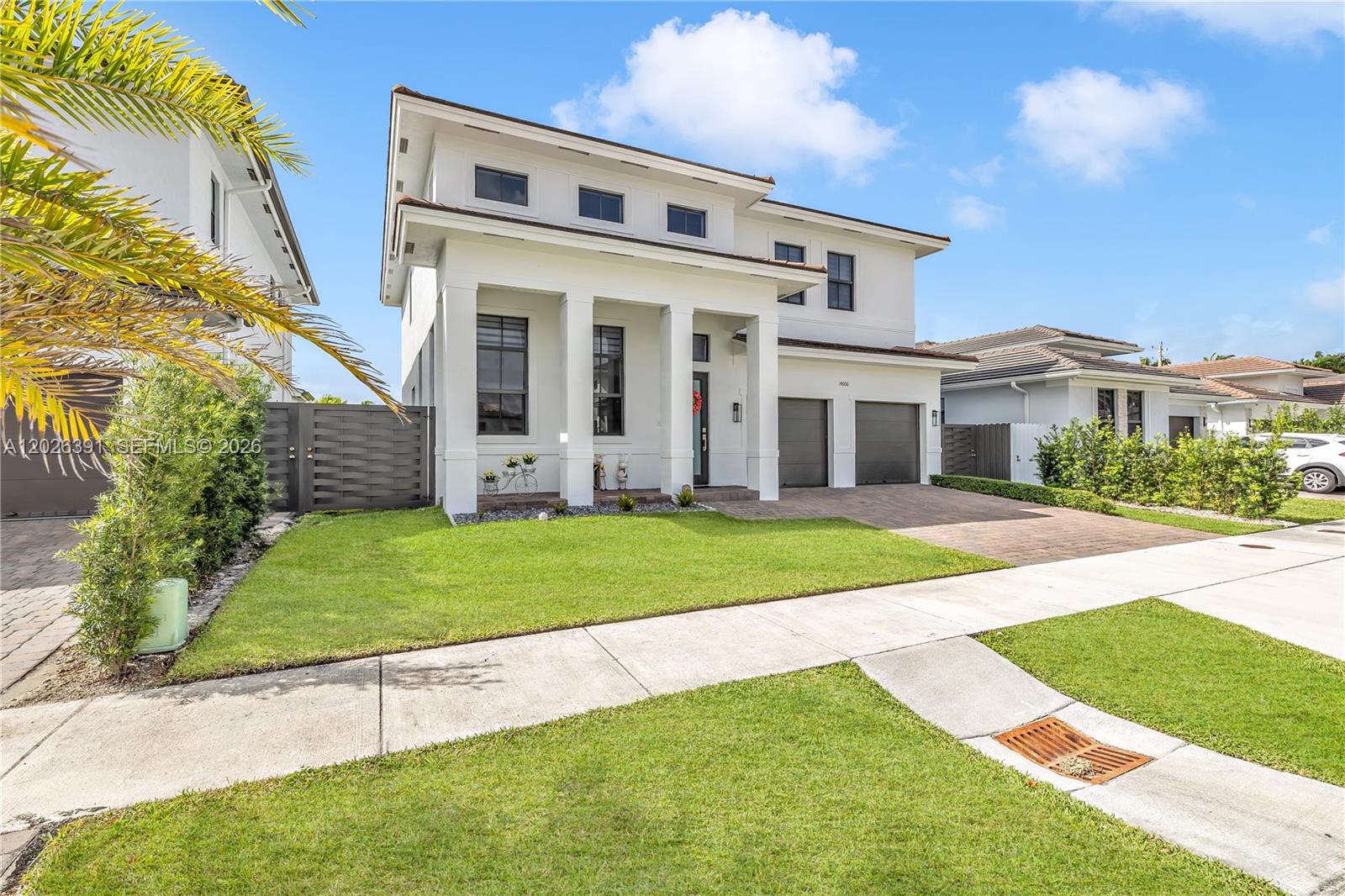 A two-story white modern house features a covered entryway, a two-car garage, and landscaping — 14606 SW 22nd Ter, Miami FL 33175, MIAMI, FL