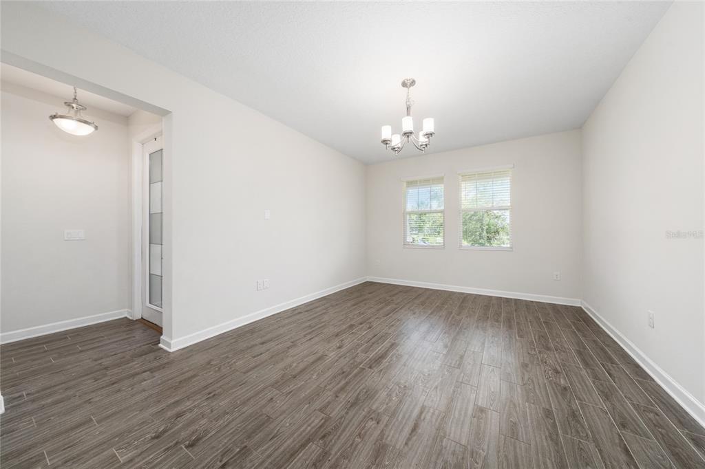A dining room with wood-look tile flooring, a chandelier, and two windows — 12066 GRAMMAR LANE, ORLANDO, FL