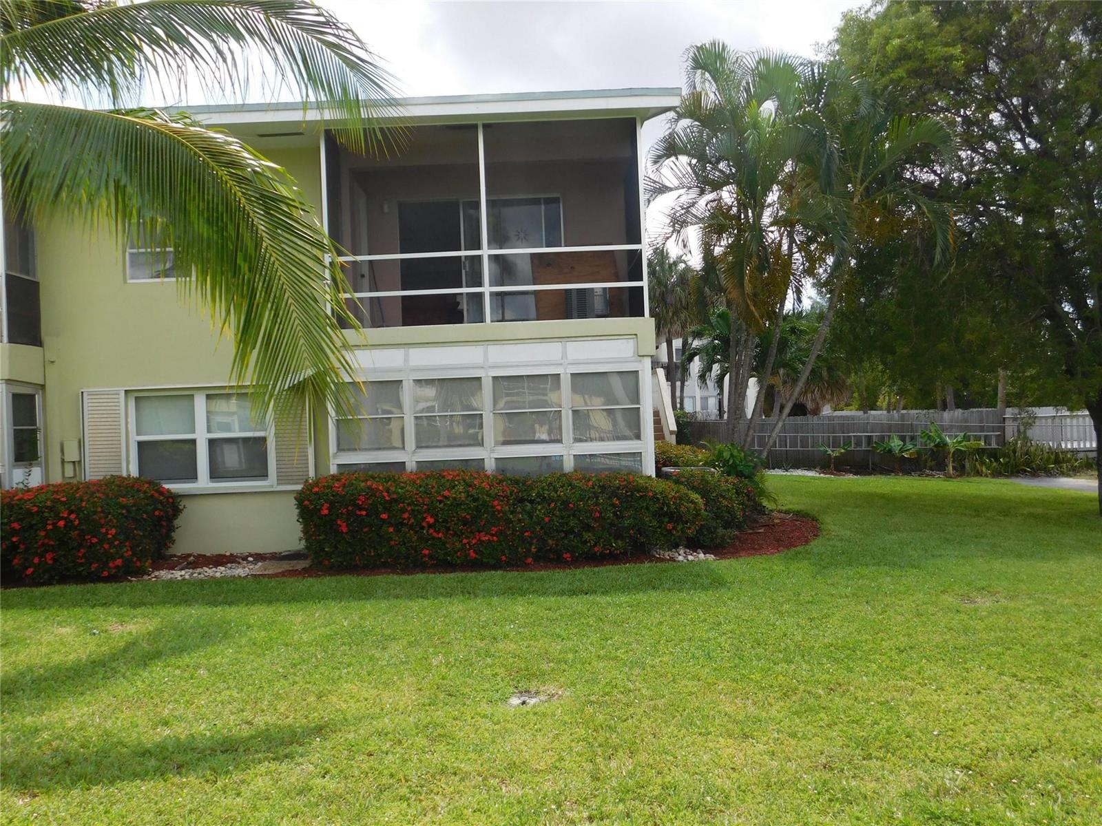 A two-story building features a screened-in balcony and a ground-floor patio surrounded by landscaping — 960 Crystal Lake Drive # 201, Deerfield Beach FL 33064, DEERFIELD BEACH, FL