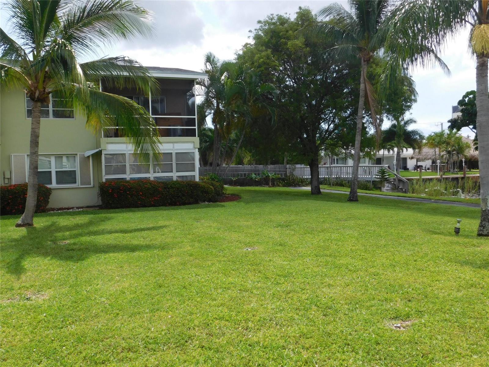 A two-story building with a screened balcony overlooks a grassy lawn and palm trees — 960 Crystal Lake Drive # 201, Deerfield Beach FL 33064, DEERFIELD BEACH, FL